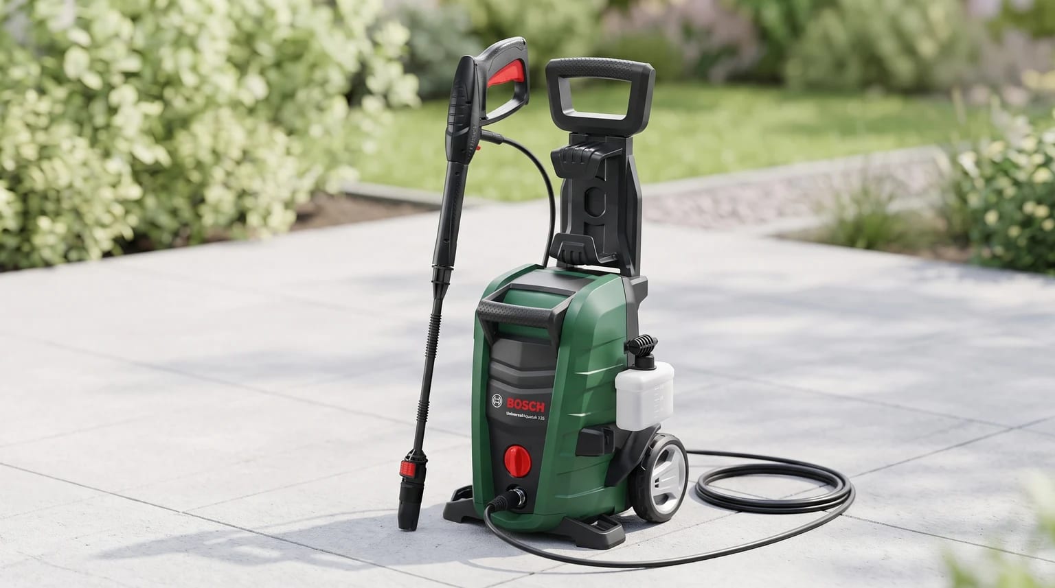A lavadora de alta pressão verde e preta da Bosch, pronta a usar num pátio pavimentado com um jardim verde desfocado ao fundo.