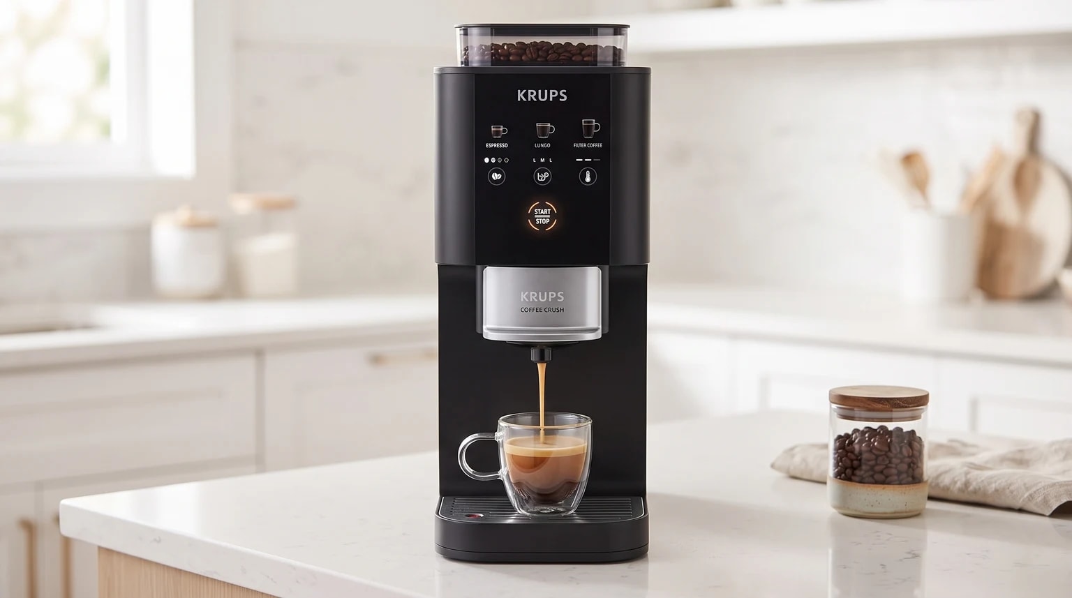 Máquina de café automática Krups preta a servir um expresso numa chávena de vidro, sobre uma bancada de cozinha branca e luminosa.