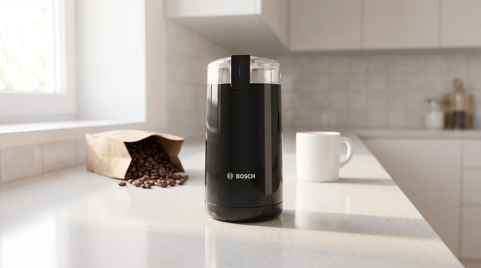Moinho de café preto da Bosch numa bancada de cozinha clara, com um saco de grãos de café e uma chávena ao lado.