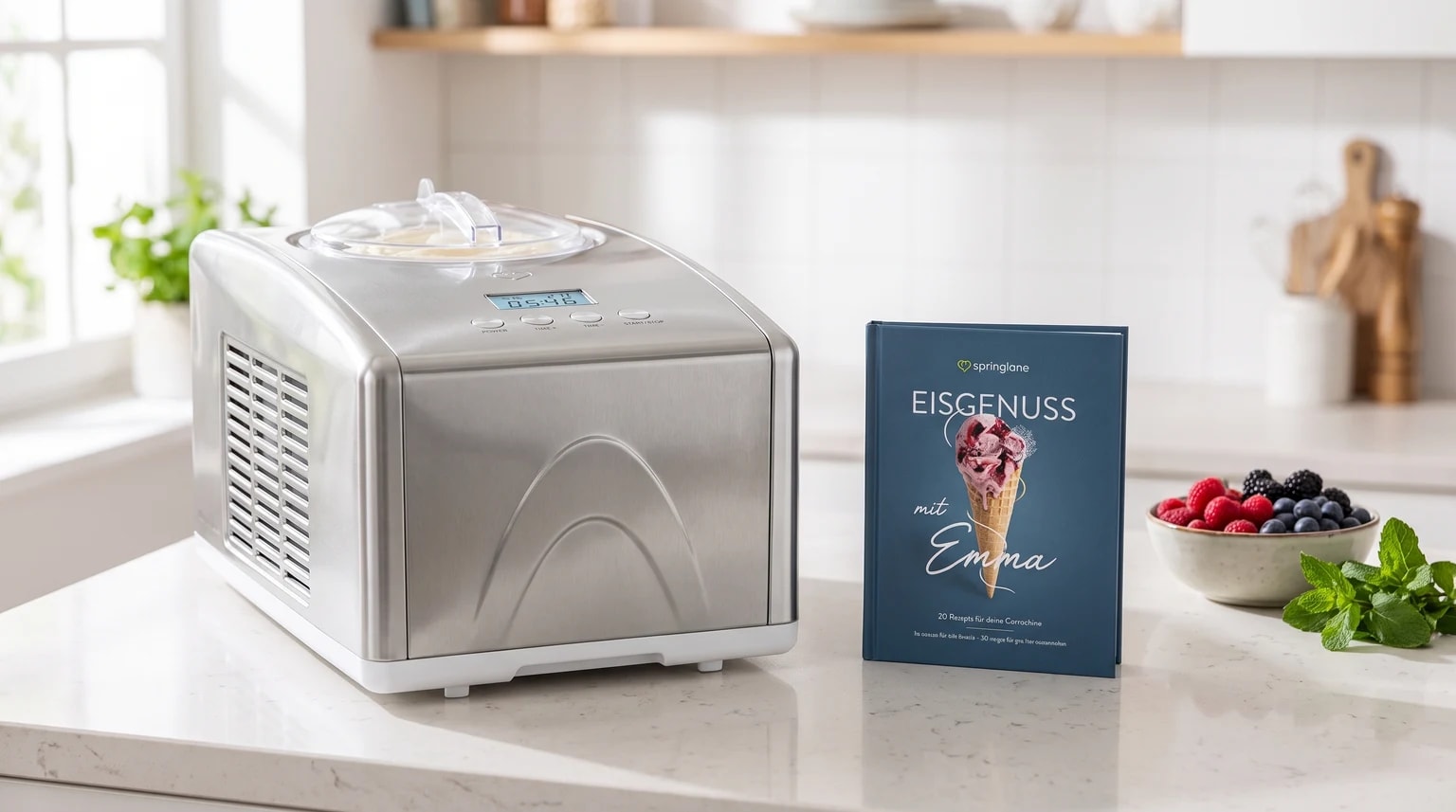 Máquina de fazer gelados Springlane Emma em inox numa bancada de cozinha, junto ao livro de receitas e a frutos silvestres.