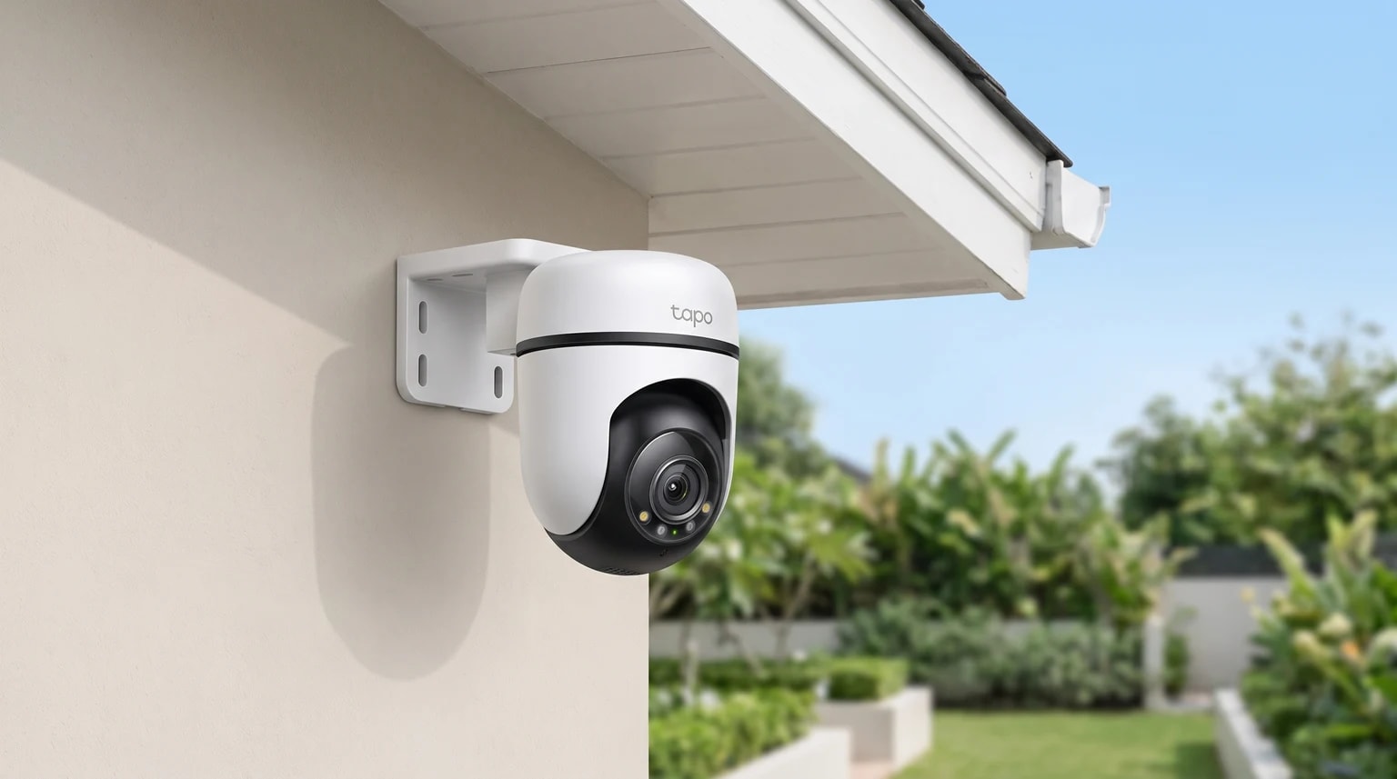 Câmara de vigilância Wi-Fi exterior Tapo C51A instalada numa parede, voltada para um jardim privado.