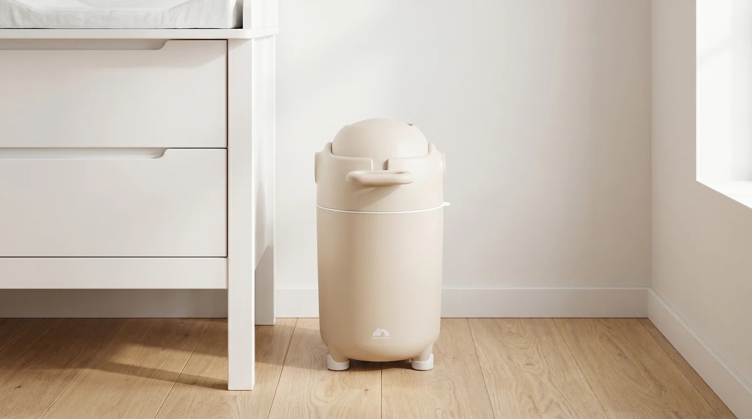 O contentor de fraldas bege Bebeconfort Easy num quarto de bebé moderno e luminoso, junto a um fraldário branco.
