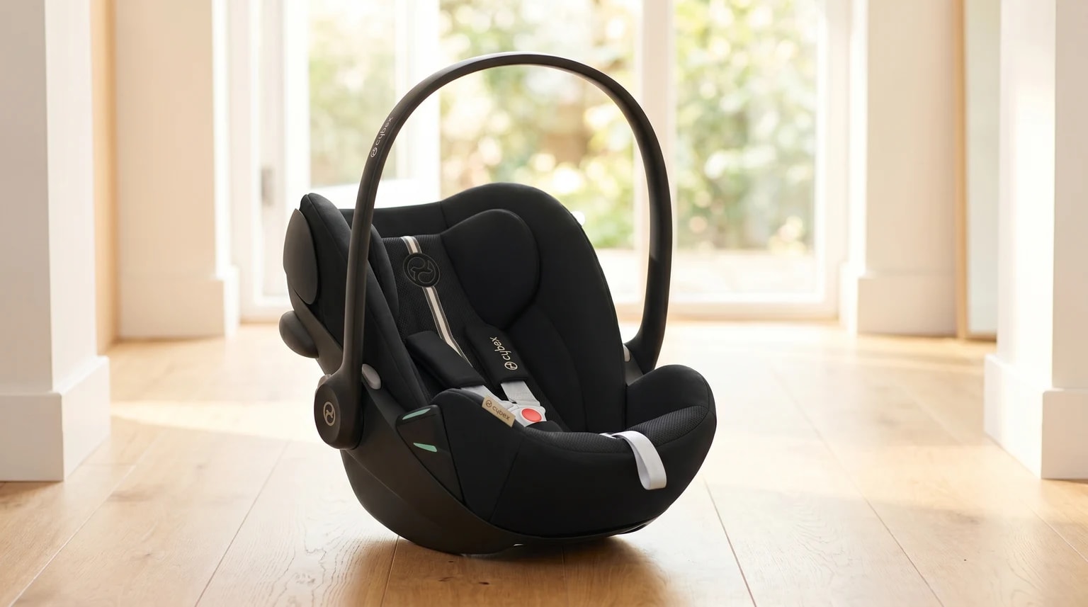 Cadeira auto para bebé Cybex Cloud G preta, pousada num chão de madeira clara numa casa moderna e bem iluminada.