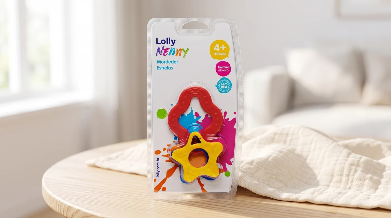 Embalagem do mordedor Lolly Nenny Estrelas nas cores vermelha, amarela e azul, sobre uma mesa de madeira em um ambiente claro.
