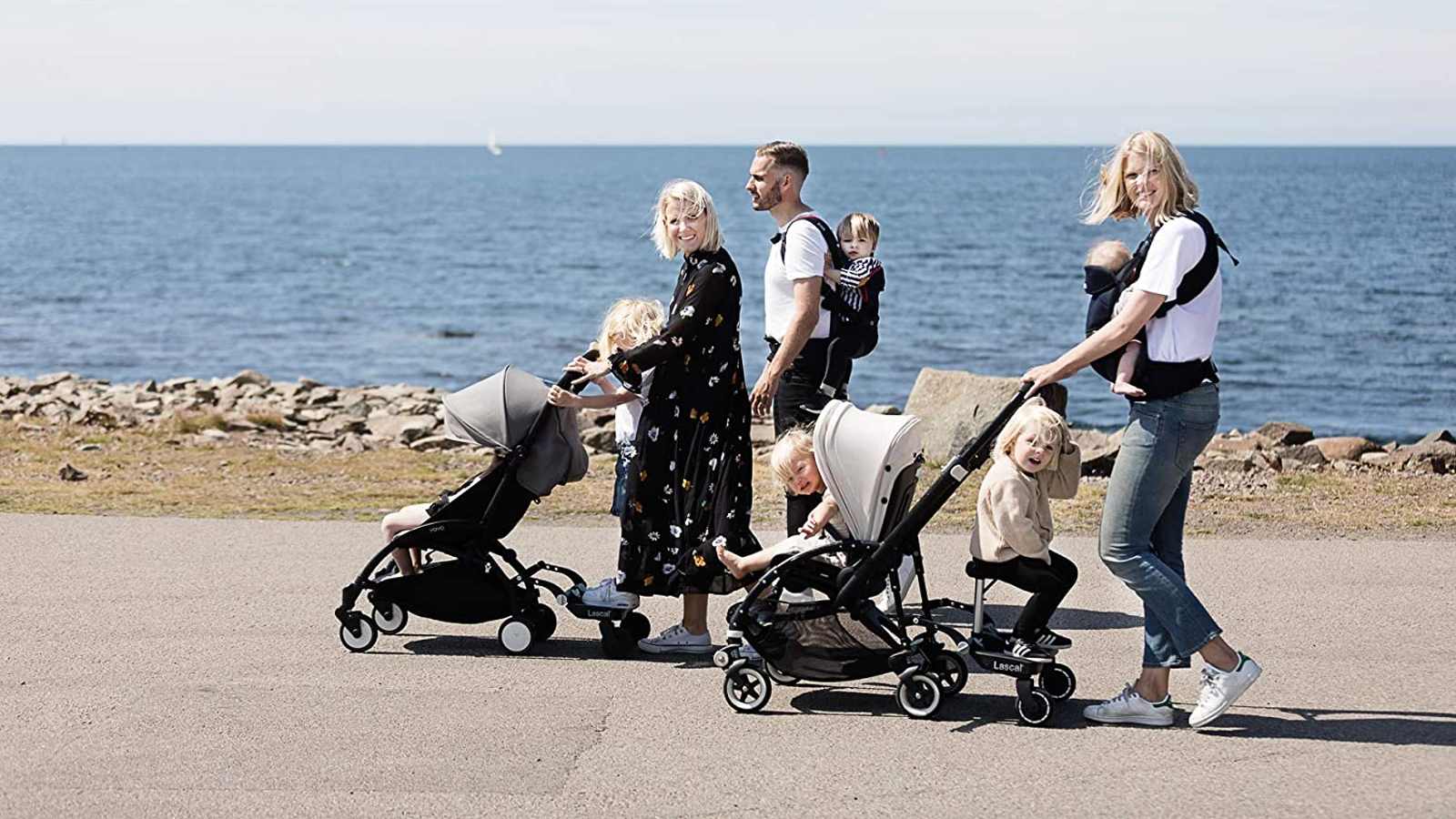 Família a passear com carrinhos de bebé equipados com plataformas trotinetes.