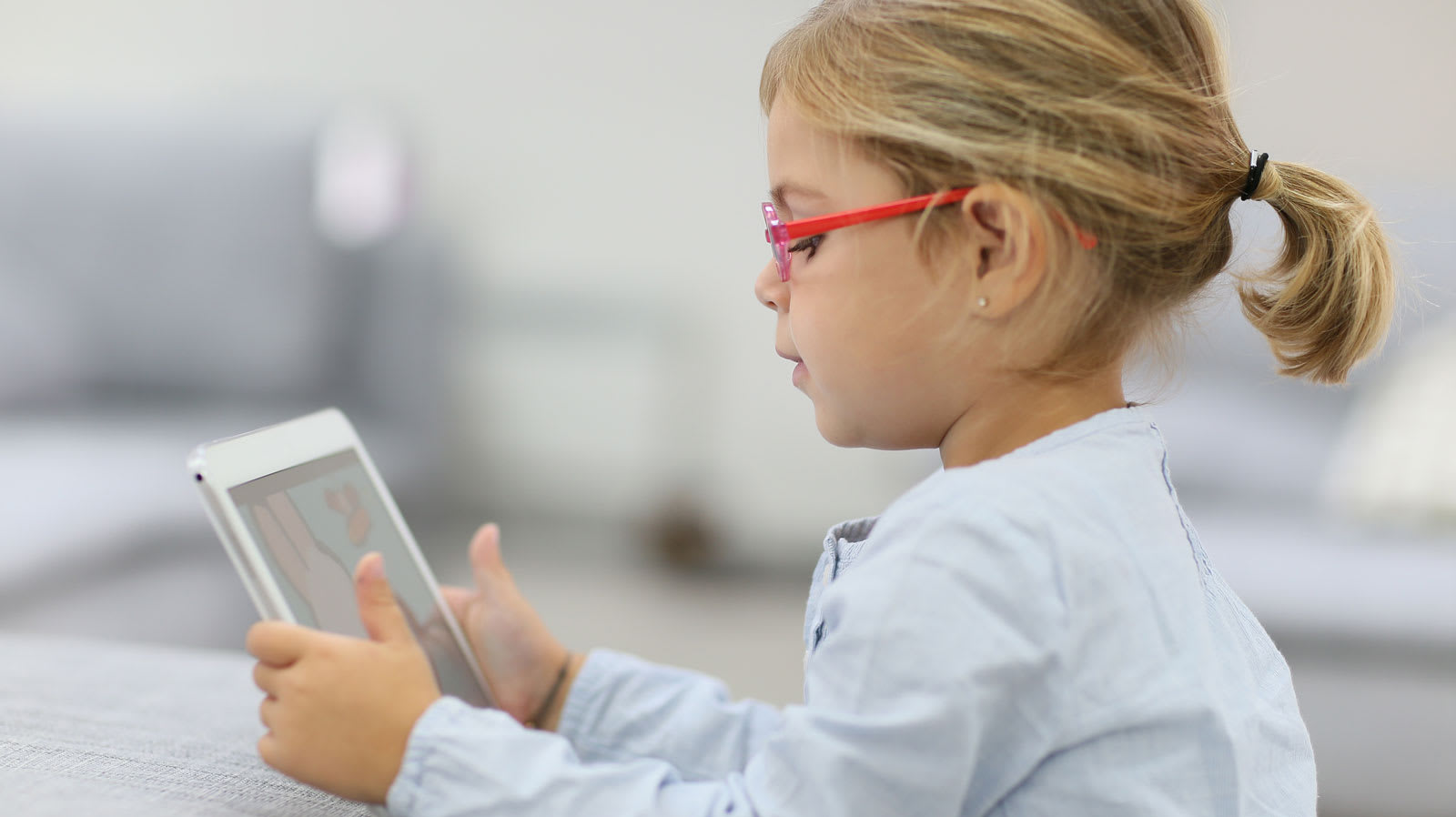 Un niño con gafas que sostiene un tablet.