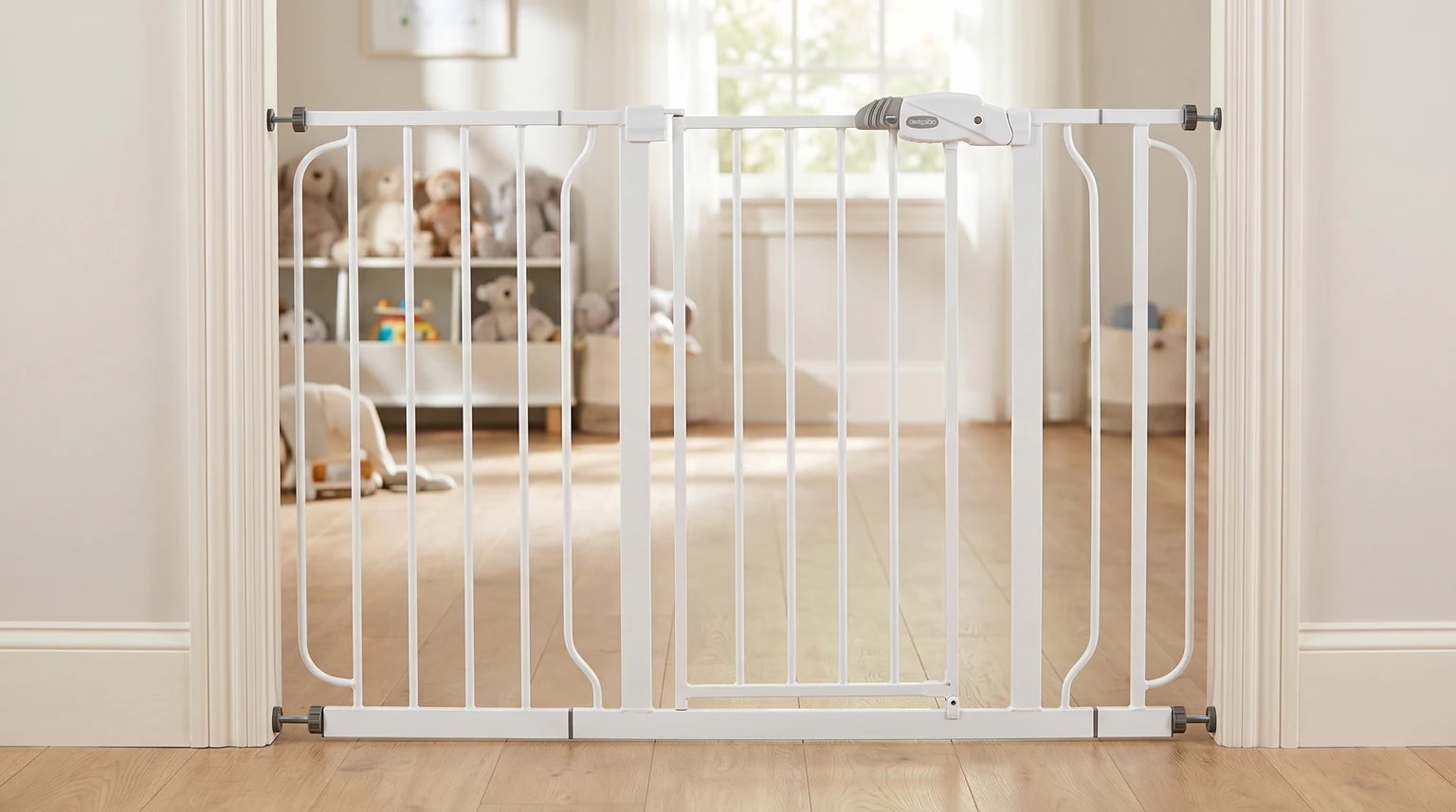 A white Regalo pressure-fit baby gate installed in a normal doorway, with a bright playroom visible beyond it.