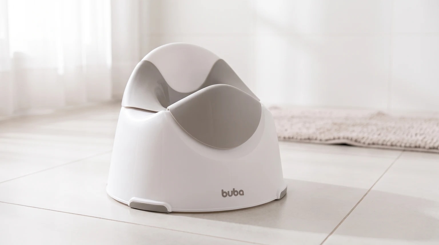 Troninho infantil branco e cinza da Buba sobre o piso de um banheiro claro, com um tapete ao fundo.