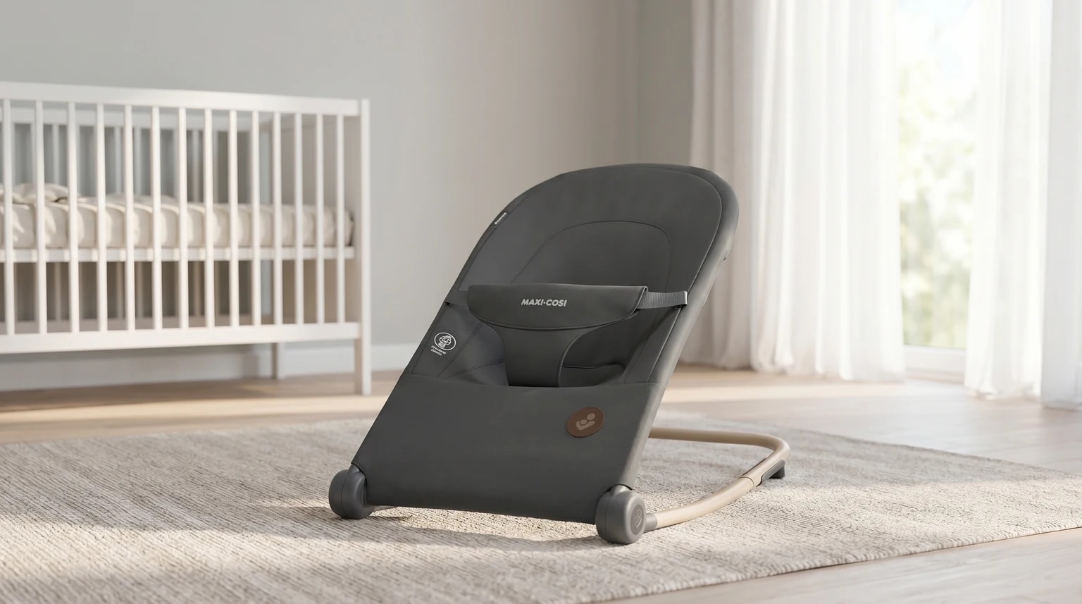 Espreguiçadeira Maxi-Cosi Loa cinzenta escura num quarto de bebé moderno e bem iluminado, junto a uma janela com luz natural.