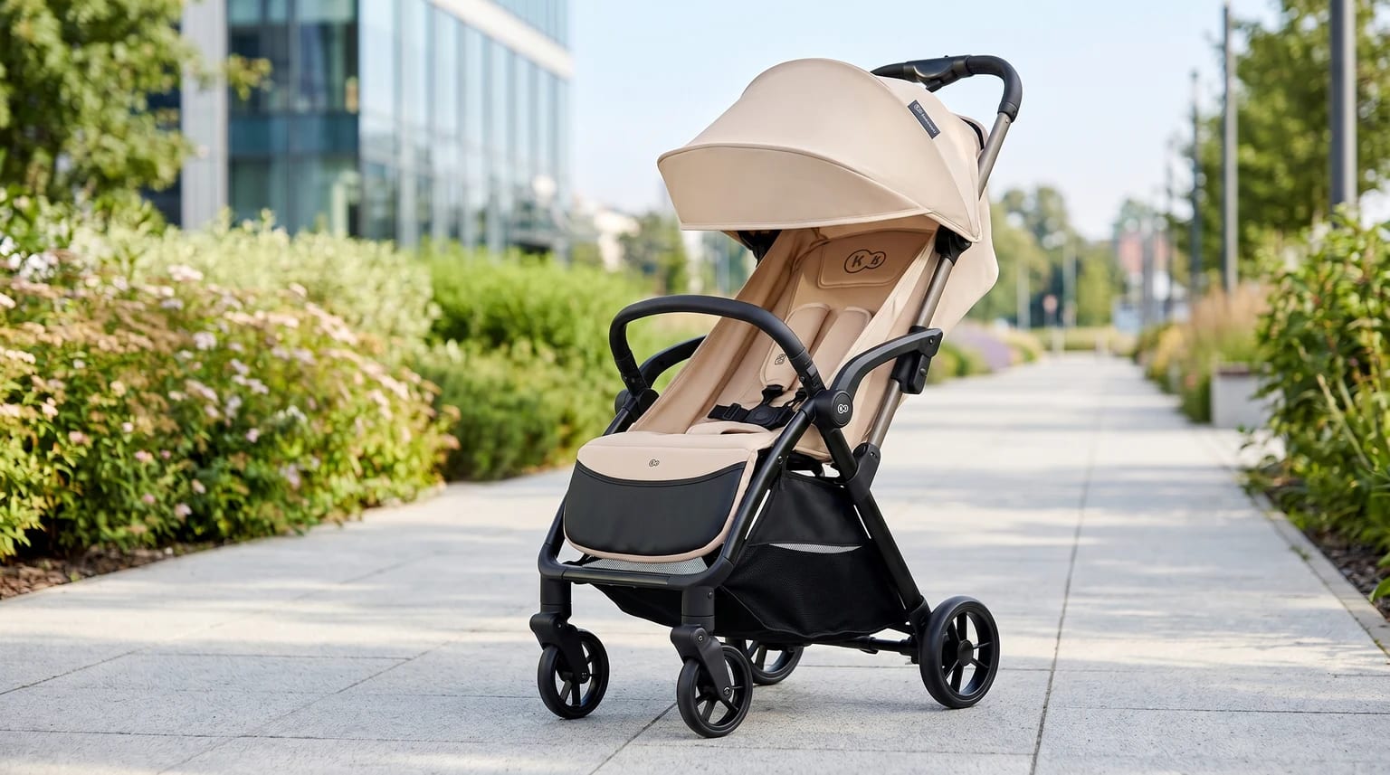 Carrinho de bebé Kinderkraft APINO em bege, num parque citadino moderno e soalheiro.