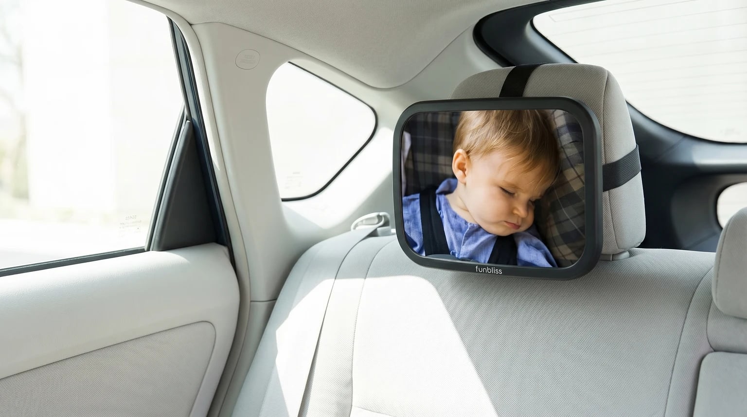 Espelho de bebé Funbliss instalado no encosto de cabeça traseiro de um carro, refletindo um bebé a dormir pacificamente na sua cadeirinha auto.