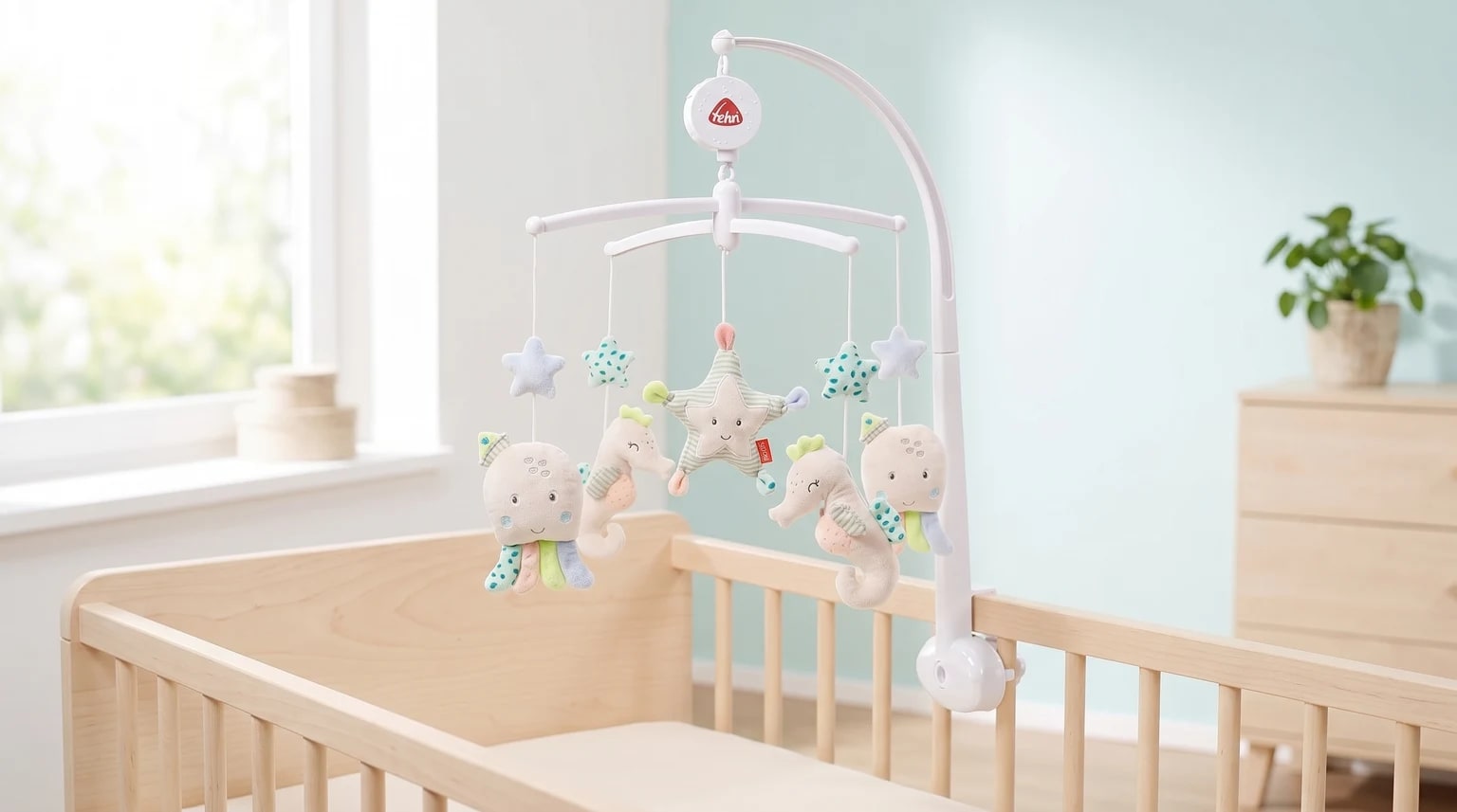 Móbile musical Fehn com animais marinhos de peluche suspenso sobre um berço branco com colchão vazio.
