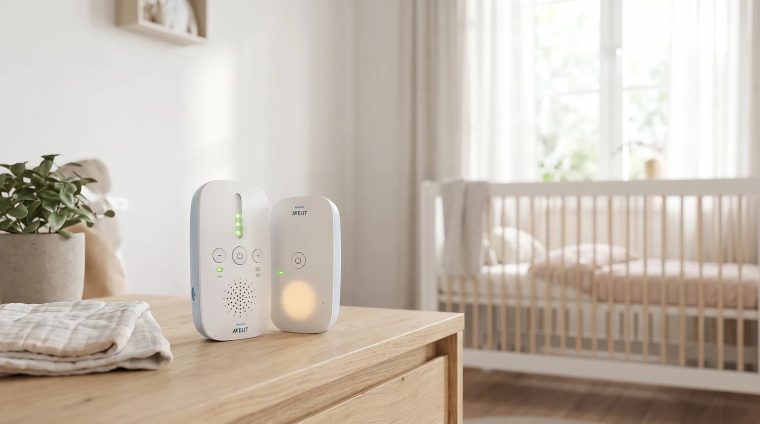 O intercomunicador de bebé Philips Avent, com as suas duas unidades, pousado numa mesa de cabeceira de madeira clara num quarto de bebé sereno e bem iluminado.