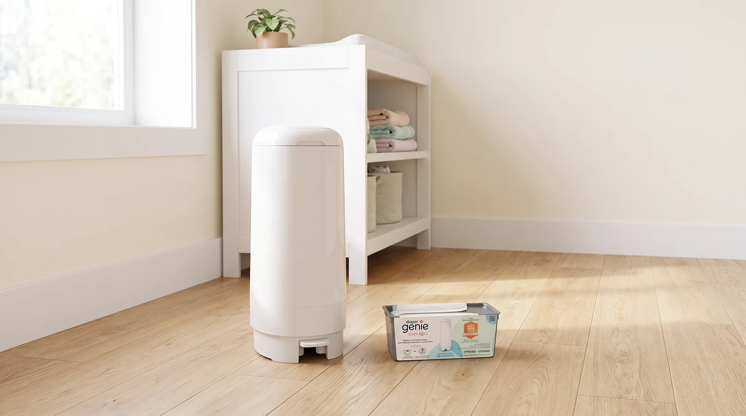 Lixeira Diaper Genie branca ao lado de um trocador, com um refil Easy Roll no chão.