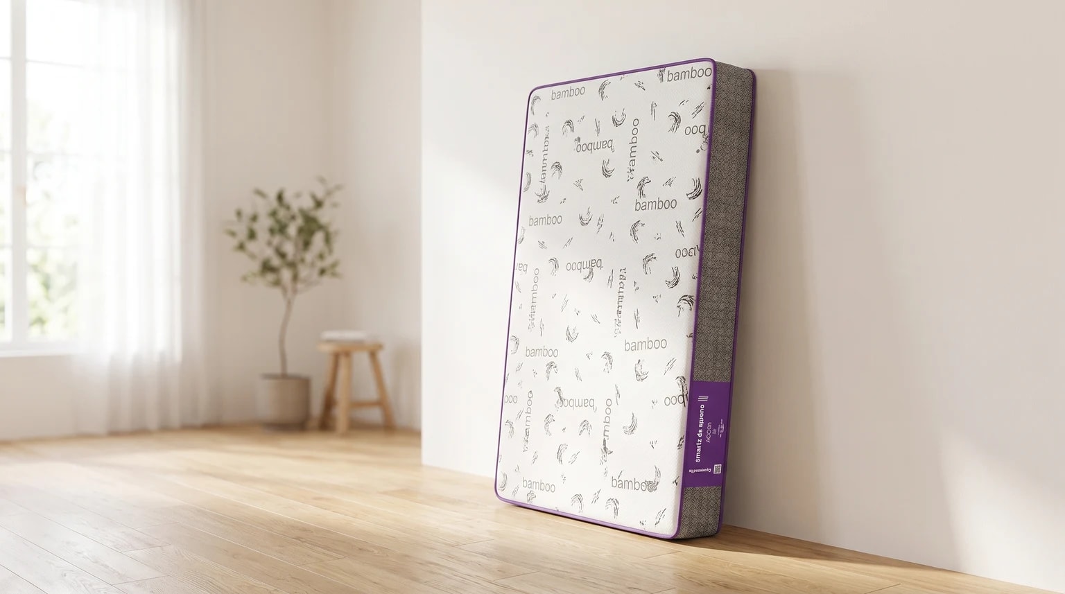Colchão de berço com a palavra “bamboo” estampada e acabamento roxo, apoiado na vertical contra uma parede em um quarto com piso de madeira.