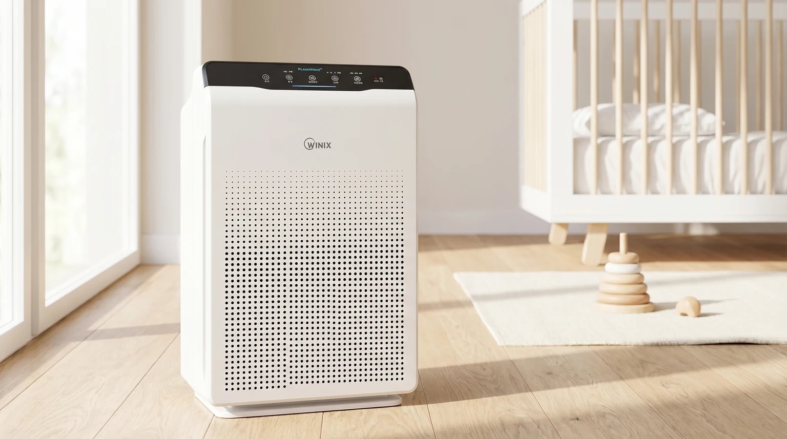Purificador de ar Winix Zero branco e preto no chão de madeira clara, ao lado de um berço branco e de um brinquedo de madeira.